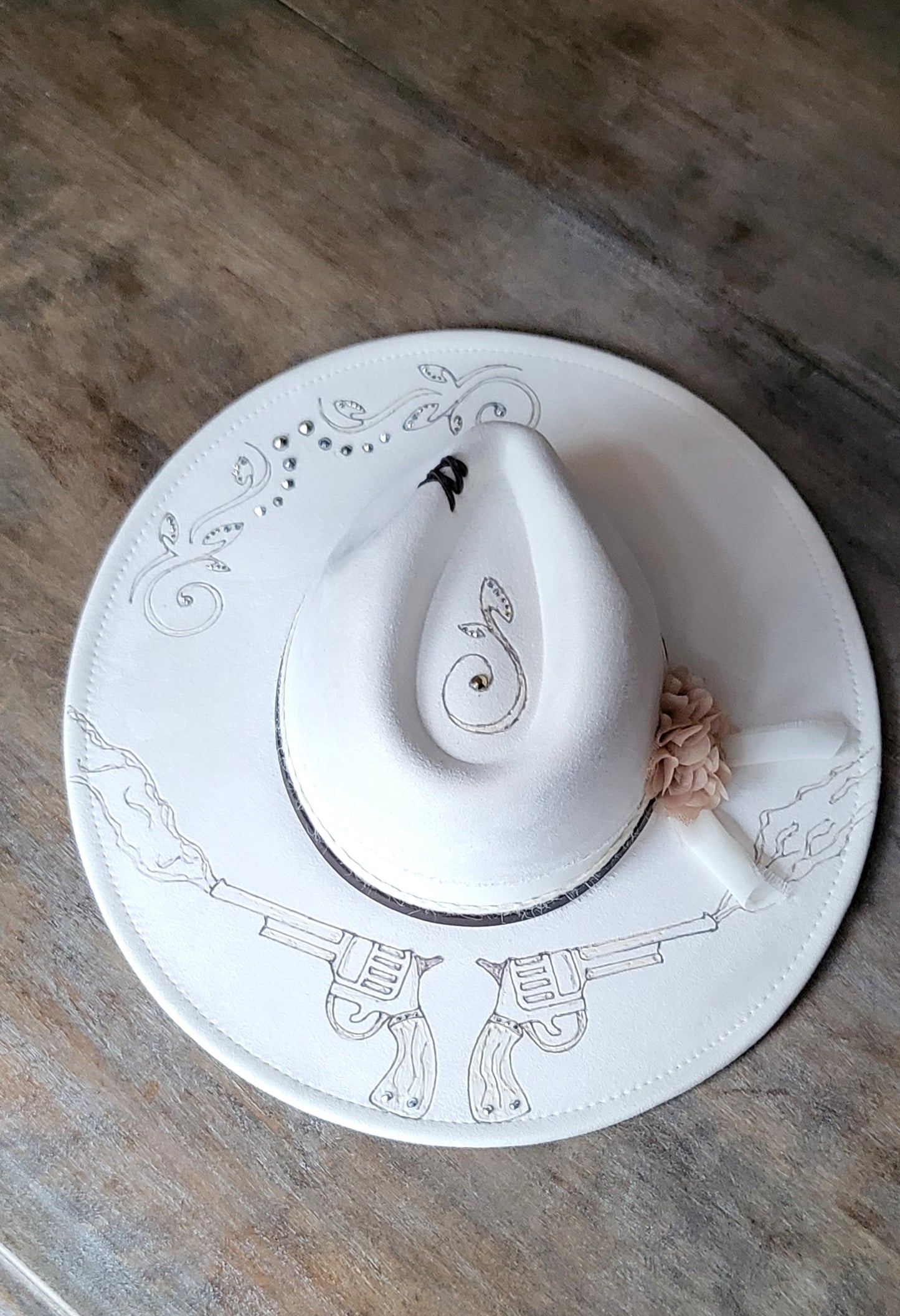 Introducing Miss "Dolly" she is a vegan suede ivory fedora.  She is hand burned and finished with rhinestones, genuine leather stitches, and hatband, then topped off with a flower and rhinestones. 
This hat would be perfect for a wedding!