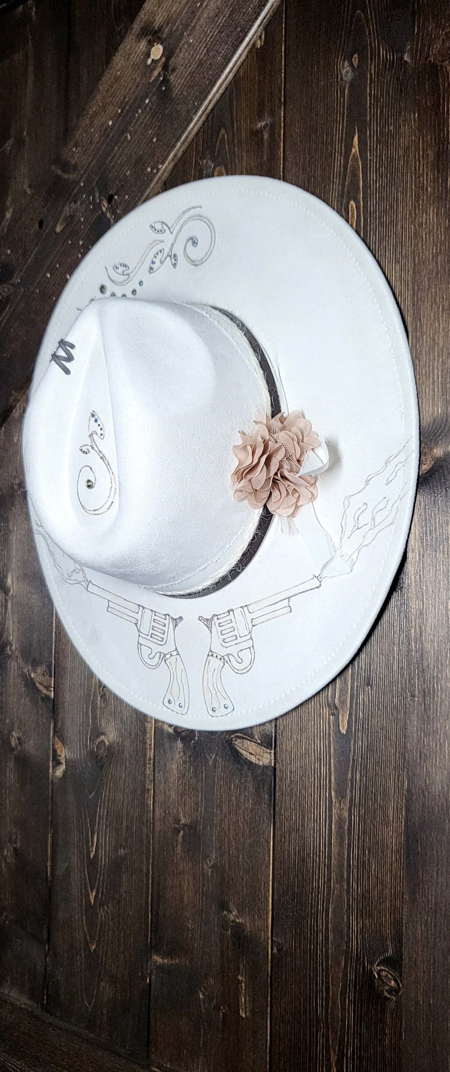 Introducing Miss "Dolly" she is a vegan suede ivory fedora.  She is hand burned and finished with rhinestones, genuine leather stitches, and hatband, then topped off with a flower and rhinestones. 
This hat would be perfect for a wedding!