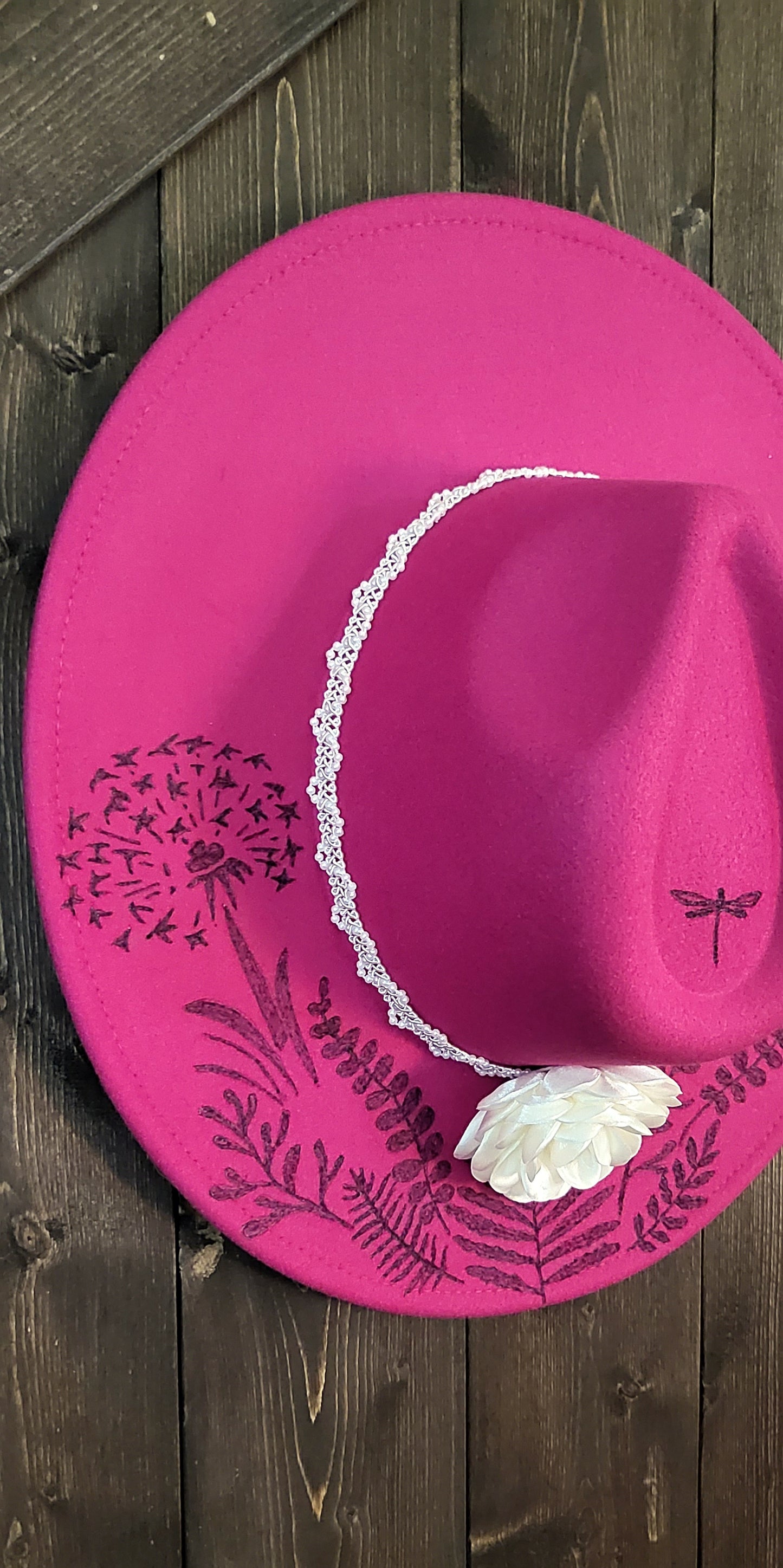 Dandelion wishes. she is hand burned with ferns and dandelions accented with a dragonfly on a raspberry, fully adjustable, vegan felt cowboy fedora hat with a pearl and silk flower hatband