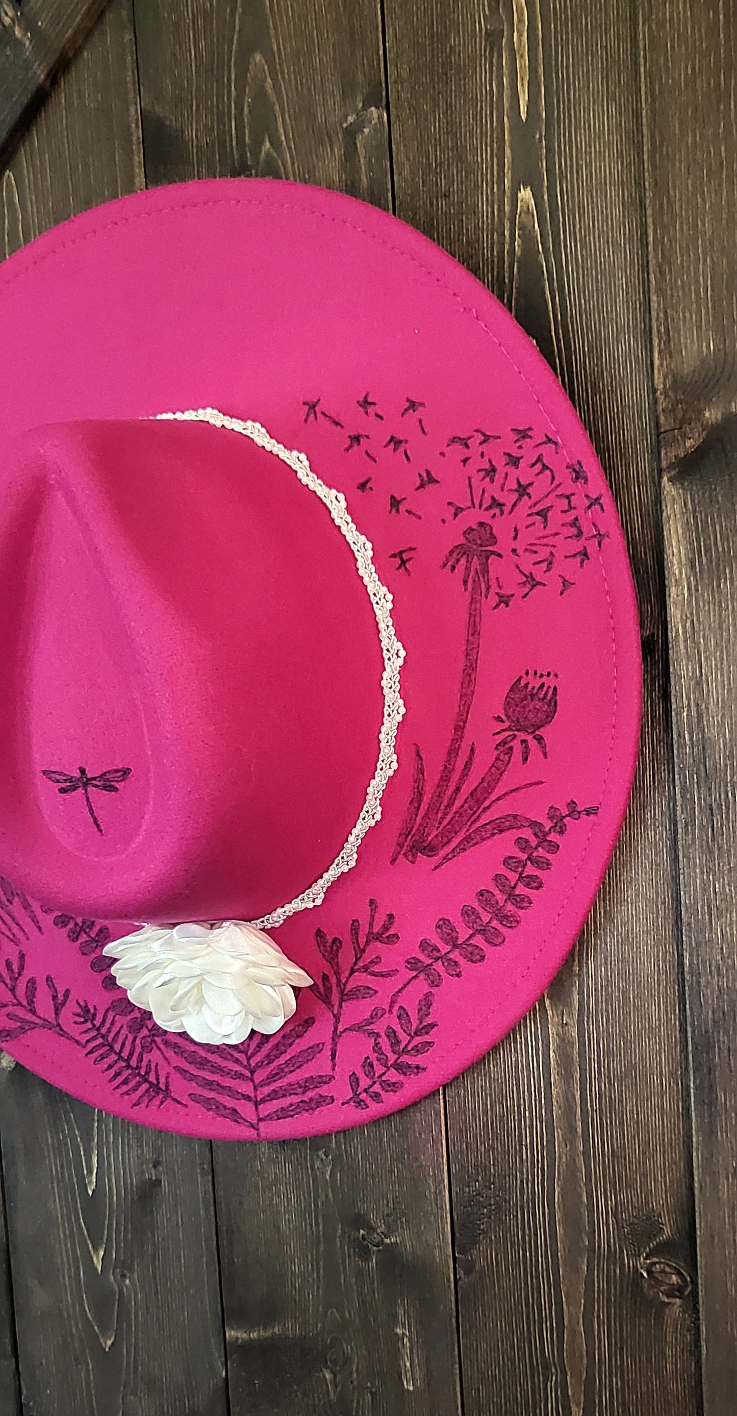 Dandelion wishes. she is hand burned with ferns and dandelions accented with a dragonfly on a raspberry, fully adjustable, vegan felt cowboy fedora hat with a pearl and silk flower hatband