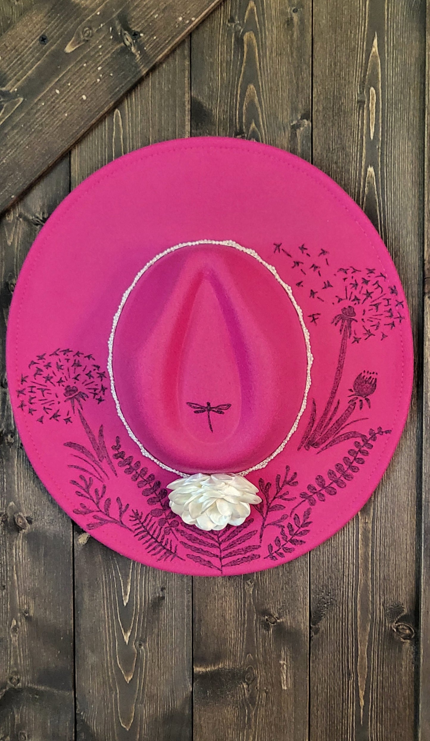 Dandelion wishes. she is hand burned with ferns and dandelions accented with a dragonfly on a raspberry, fully adjustable, vegan felt cowboy fedora hat with a pearl and silk flower hatband